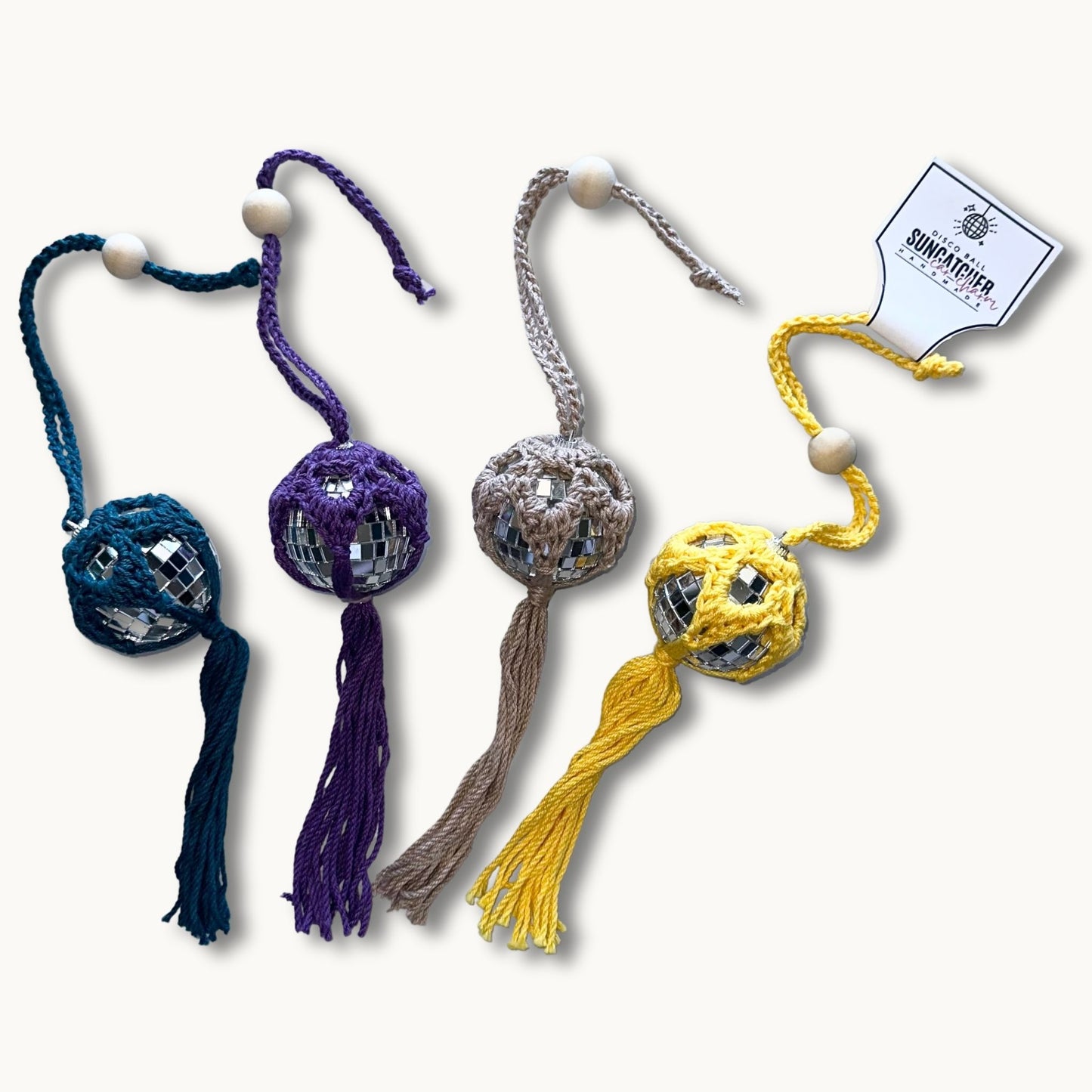 A collection of handmade crochet car charms with a disco ball design, featuring various colors and patterns, attached to a looped tie for hanging in a car's rearview mirror.