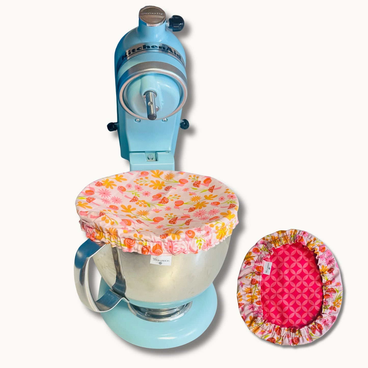 Blue stand mixer with floral and pink covers with mushrooms and snails on a white background